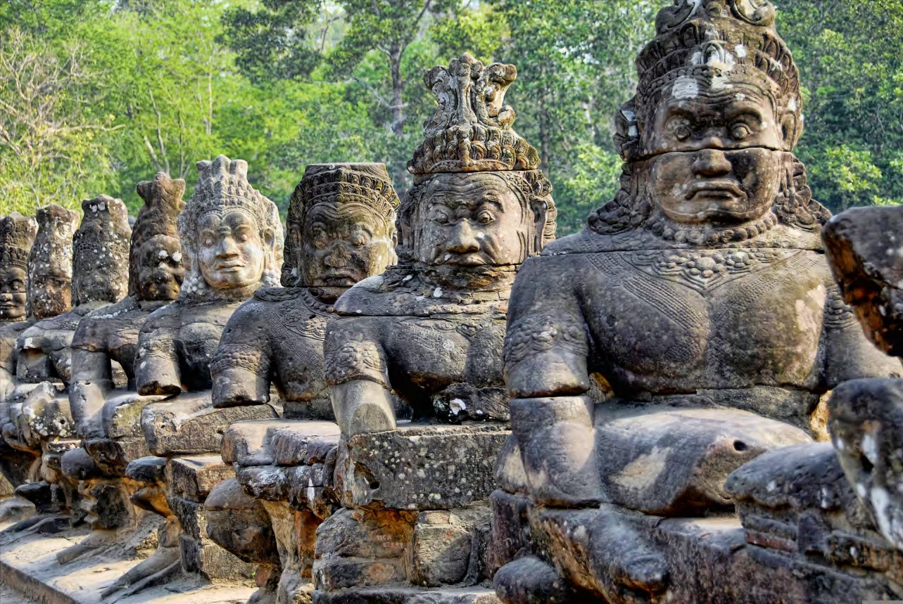 Hilera de gigantes de piedra con rostros tallados en el puente de entrada a Angkor Thom