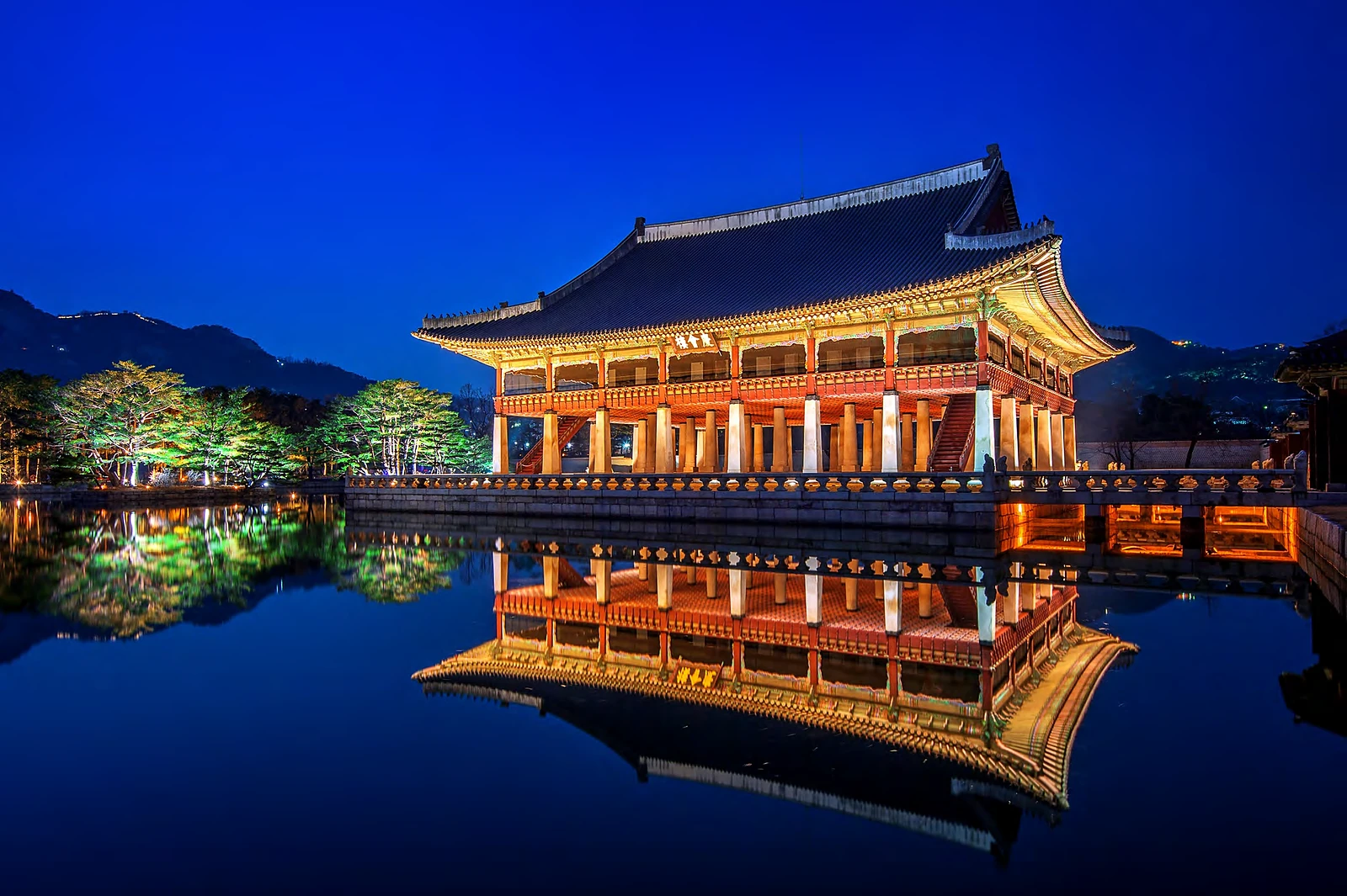 El pabellón Gyeonghoeru del palacio Gyeongbokgung, iluminado de noche y reflejado en el estanque