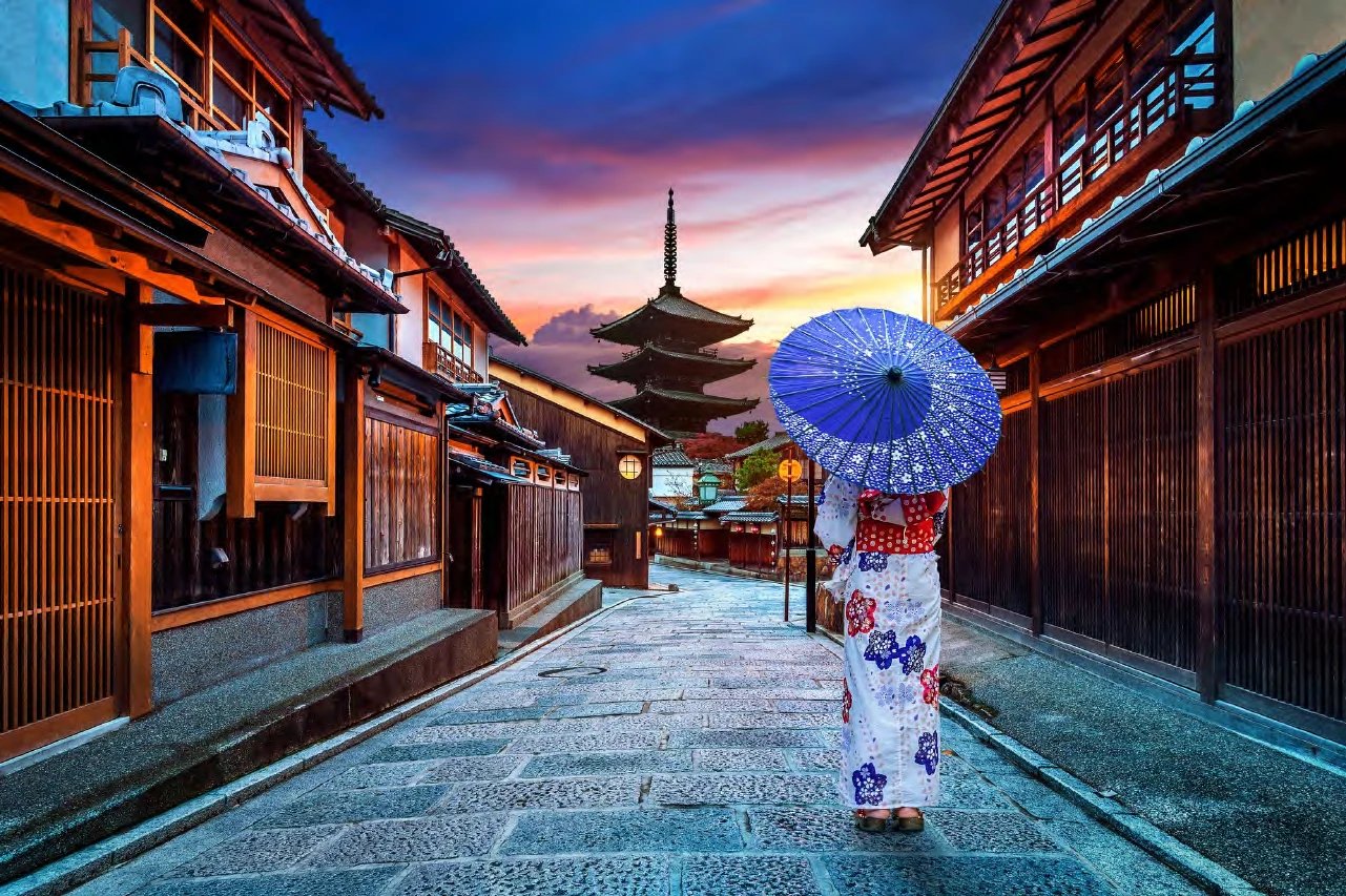 Una mujer en kimono con sombrilla en una calle empedrada de Kioto, frente a la pagoda Yasaka