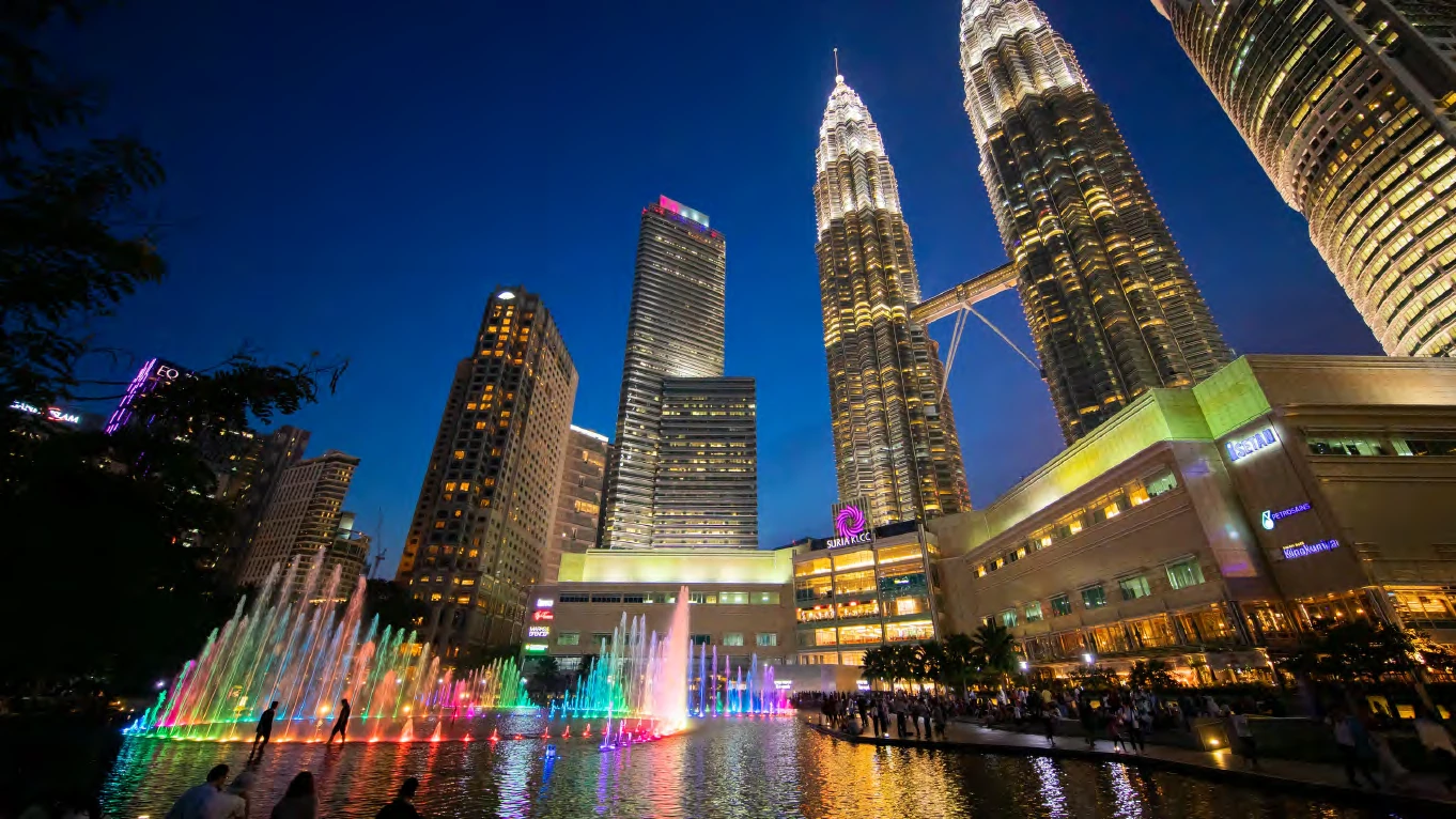 Las torres Petronas iluminadas de noche, con las fuentes de colores del parque KLCC
