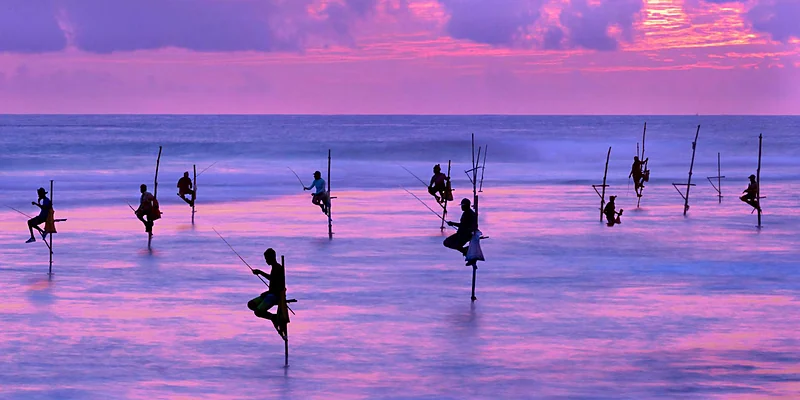 Pescadores sobre zancos al atardecer en la costa sur