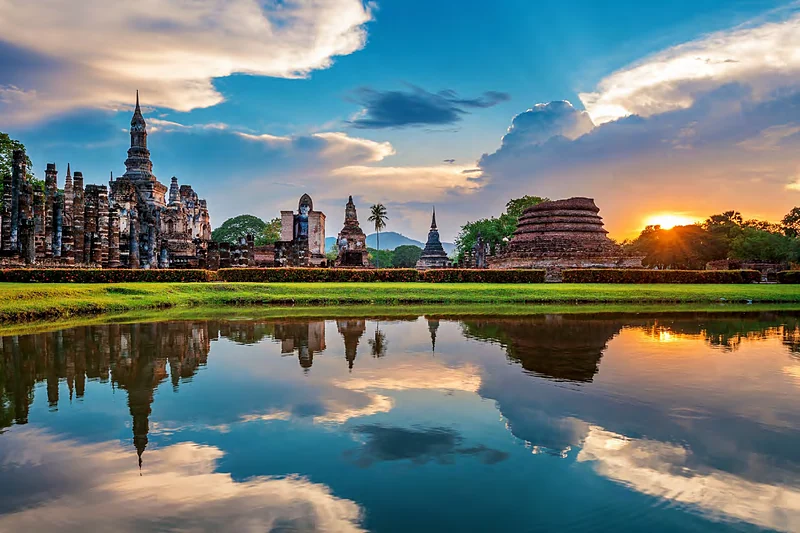 Ruinas de Sukhothai reflejadas en el agua al atardecer